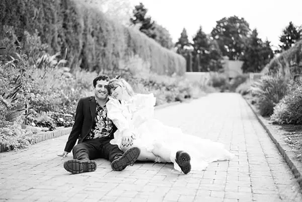 Black and white portrait of a smiling bride and groom sitting together on a brick path